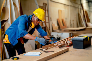 African American carpenter man hold and check tool for wood working and stay in factory workplace.