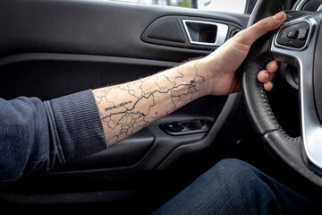 Original biker tattoo in the form of a route. Motorcycle tattoo. Ink drawing on the body. Hand on the wheel. Lay the route.