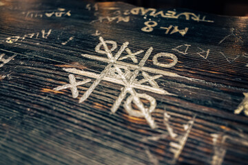 A game of tic-tac-toe on a wooden bar counter. A tic-tac-toe game for two. Combinatorial theory....