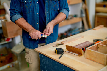 Close up hands of carpenter man use cutter knife to sharpener pencil before work with wood product...