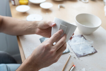 Close-up Image of male hands working with clay mug and making Ceramic Product. Professional Ceramic Artist makes handcrafted products. Small business and hobby concept