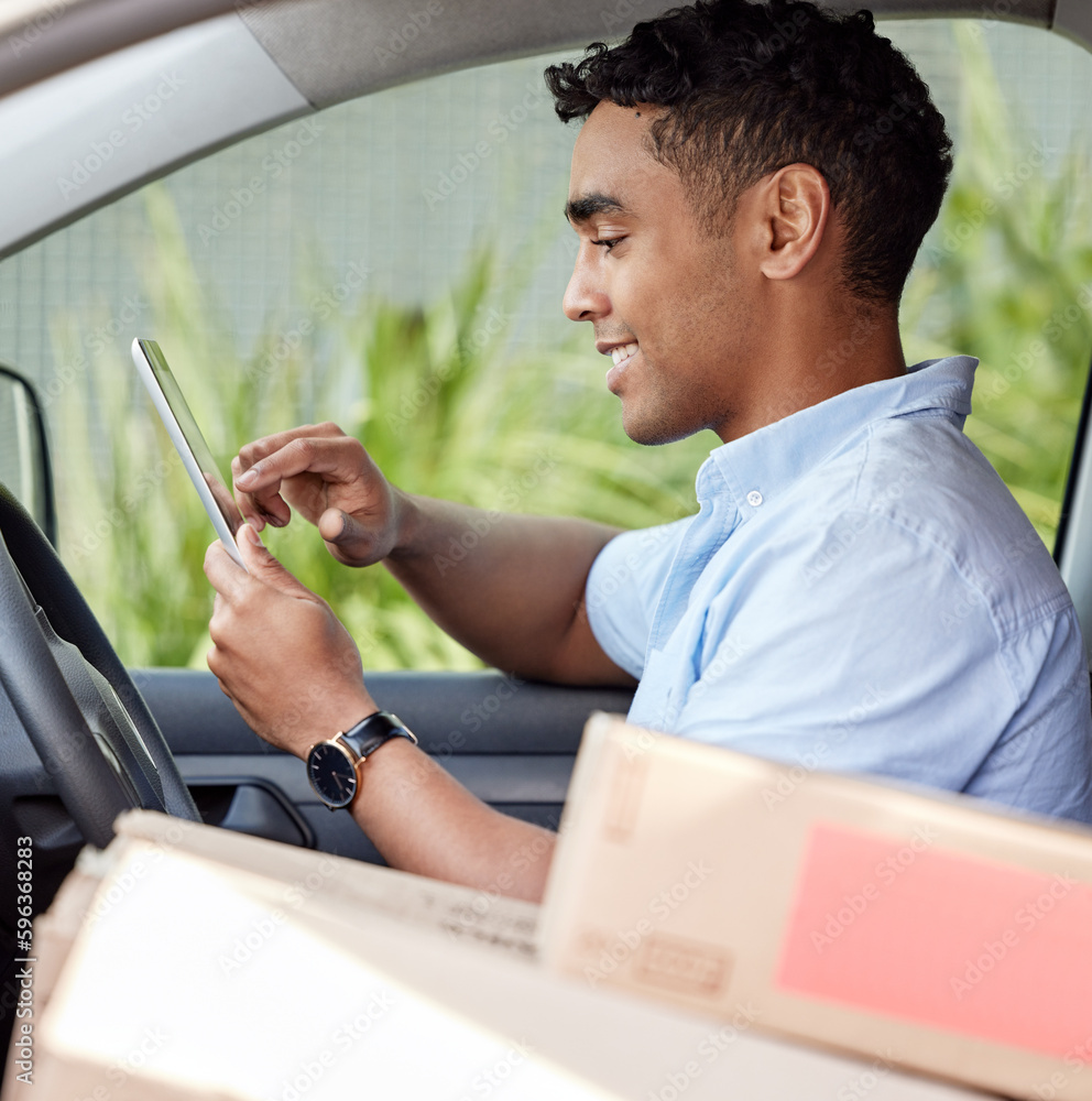 Poster Monitoring it all on his digital system. Shot of a young delivery man using a digital tablet while sitting in a van.