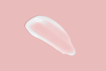 A dab of cosmetic cream. Light, smooth surface. Texture of spreadable cream. Liquid cream smear. On a pink background.