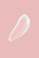 A dab of cosmetic cream. Light, smooth surface. Texture of spreadable cream. Liquid cream smear. On a pink background.