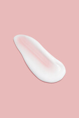 A dab of cosmetic cream. Light, smooth surface. Texture of spreadable cream. Liquid cream smear. On a pink background.