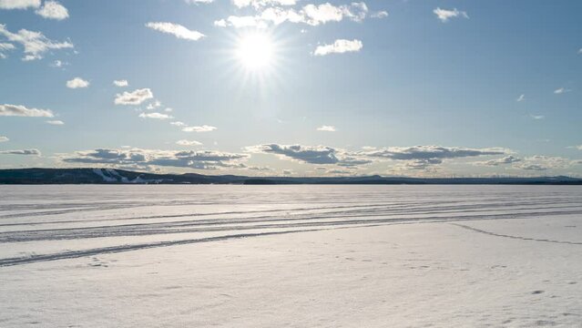 Sunny Day in surroundings of town Pitea during Springtime With Clouds in movement over frozen Snowy Lake in Northern Sweden 