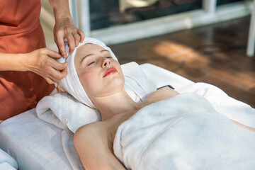 Caucasian ladies wore towels Lying on the bed, the masseuse wrapped her hair in the hands of the masseuse in preparation for a facial massage and facial treatment at the spa and wellness.
