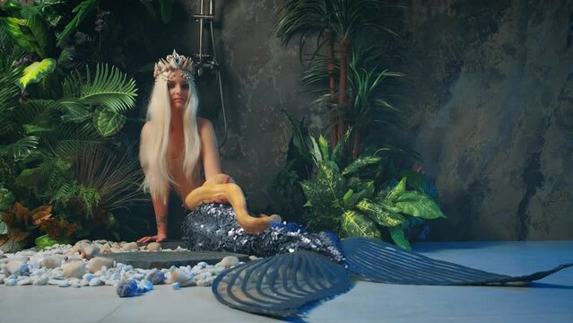 Close-up art portrait woman mermaid with snake. Nagga goddess touches white milk Boa constrictor. Fantasy asp girl blonde long hair, looks at serpent. Lady goth vampire queen viper. green palants. 4k