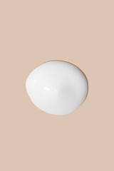 The flowing cream on a beige background. Smudged flowing smear of cosmetic cream.