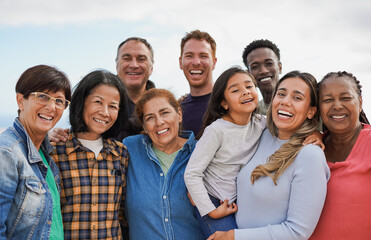 Group of multigenerational people hugging each other while smiling on camera - Multiracial friends having fun together outdoor - Powered by Adobe