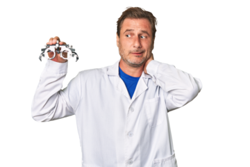 A middle-aged optometrist man touching back of head, thinking and making a choice.