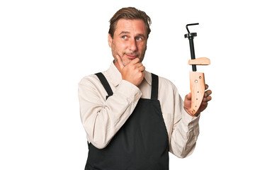 Naklejka premium A middle-aged shoe maker looking sideways with doubtful and skeptical expression.