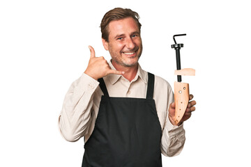 A middle-aged shoe maker showing a mobile phone call gesture with fingers.