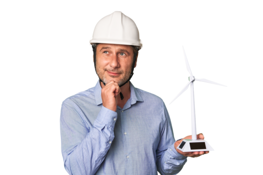 A middle-aged architect man holding a windmill model looking sideways with doubtful and skeptical expression.