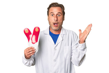 A middle-aged podiatrist holding an insoles
