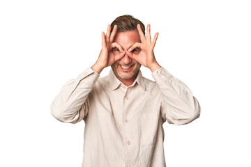 A middle-aged man isolated showing okay sign over eyes