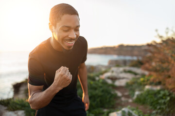 Smiling strong excited millennial african american man doing success and victory gesture with hand