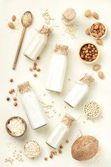 Fototapeta na wymiar Non dairy plant based milk in bottles and ingredients on light background. Alternative lactose free milk substitute, flat lay