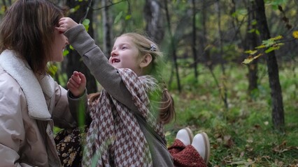 Hello September. A young mother and little daughter walk in the city park in autumn.
