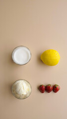 cream, lemon, coconut milk, strawberry in a flat lay style, aesthetic ingredients, isolated on light brown background, top view