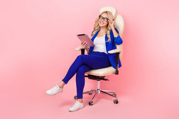 Full photo of young businesswoman touch eyeglasses chair hold notepad wear blue suit look empty space google search isolated on pink color background