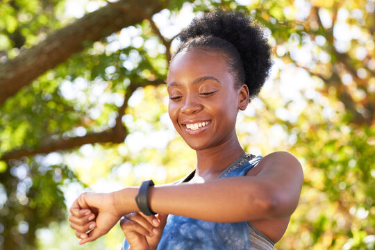 Close Up Of Black Woman Smiling And Checking Fitness Watch Outside In Park Trees