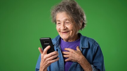 Funny crazy portrait of toothless old elderly grandmother having video chat with family and friends over internet isolated on green screen background
