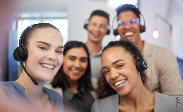 Were all eager to answer your calls. Portrait of a group of call centre agents taking selfies in an office.