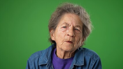 Fototapeta premium Closeup of thinking thoughtful elderly old toothless woman with idea on green screen background.