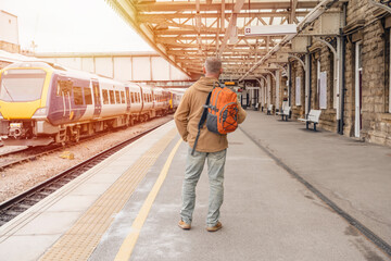 Traveler with a backpack waiting for a train at the train station.   Travel concept.