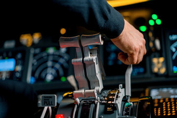 Close-up of a pilot's hand pressing the throttle in the cockpit of a jet plane reducing engine power