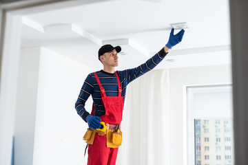 man plasterer construction worker at work, takes plaster from bucket and puts it on trowel to...