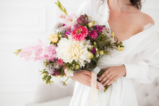 Wedding bouquet in the hands of the bride, white dress, boho style, ribbons