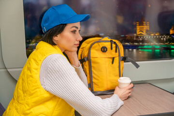 Young woman in a yellow waistcoat and yellow backpack traveling by train Enjoying travel concept