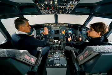An experienced pilot instructs a young student before a training flight in the cockpit of an aero simulator - obrazy, fototapety, plakaty