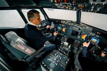 An experienced pilot instructs a young student before a training flight in the cockpit of an aero...