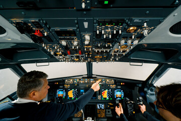 An experienced pilot instructs a young student before a training flight in the cockpit of an aero simulator © Guys Who Shoot