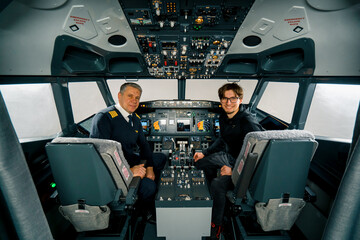 airplane cockpit pilot and young student boy smiling after training on flight simulator...