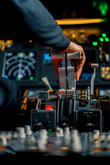 Close-up of a pilot's hand pressing the throttle in the cockpit of a jet plane reducing engine power