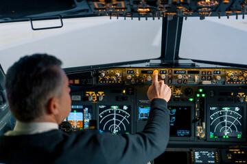 The pilot presses the power buttons on the control panel to control the aircraft in front of the cockpit windshield - obrazy, fototapety, plakaty