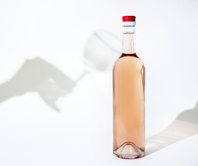 rose wine bottle isolated and hard light forming a hand shadow that want to touch take the bottle.woman girl holding bottle upside down in party dress with glitter,sequins.empty glass
