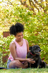 A multi-ethnic woman and her happy dog, giving attention in the park pet owner