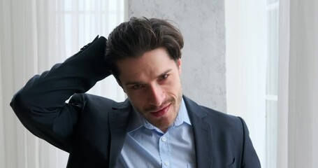 Portrait of handsome young businessman smiling and fixing his hair