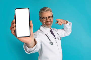 Smiling grey-haired caucasian doctor showing phone with blank screen