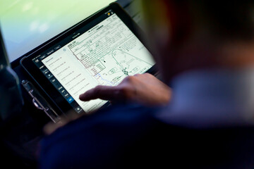 the pilot holds a tablet in his hands, looks at the flight route and chooses the landing place of the plane