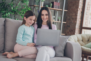 Photo of mommy sit cozy couch with kid girl use netbook browsing toy on website in modern apartment...