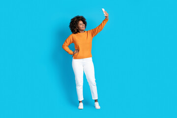 Cool stylish young black woman taking selfie on smartphone