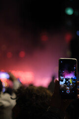 Fototapeta na wymiar Mobile phone recording vertically at a concert red lights 