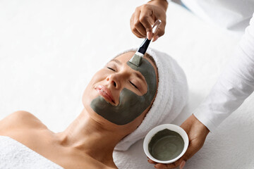 Cosmetology. Beautician At Spa Salon Applying Clay Mask To Middle Aged Woman