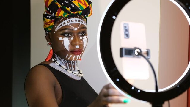 African woman working on social media with mobile phone and tripod